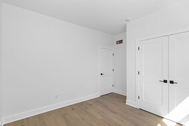 unfurnished bedroom with baseboards, a closet, and light wood-type flooring