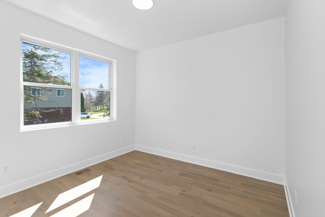 empty room featuring wood finished floors, a wealth of natural light, and baseboards