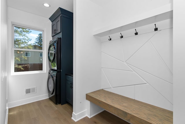 mudroom featuring light wood-style flooring, visible vents, baseboards, and stacked washer / drying machine