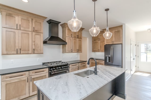 kitchen featuring wall chimney range hood, light brown cabinetry, stainless steel appliances, and a sink