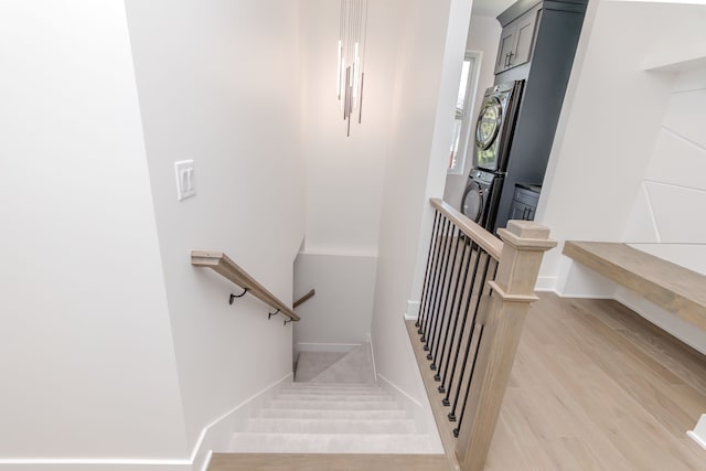 stairs featuring stacked washing maching and dryer, baseboards, and wood finished floors