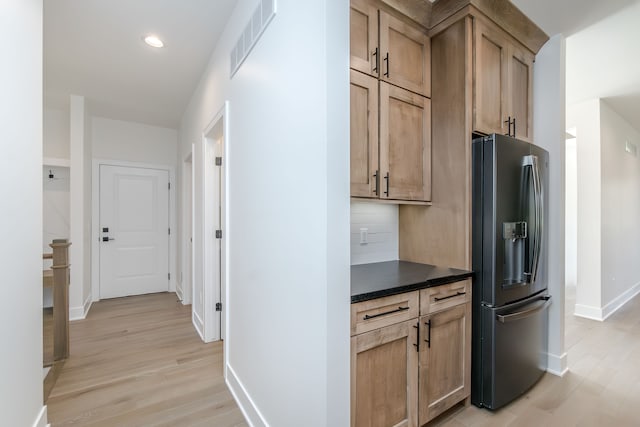 kitchen with dark countertops, stainless steel fridge with ice dispenser, light wood finished floors, baseboards, and visible vents
