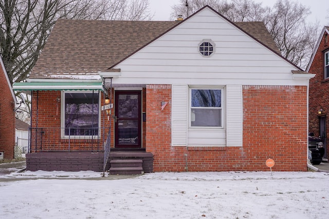 bungalow-style house with roof with shingles and brick siding