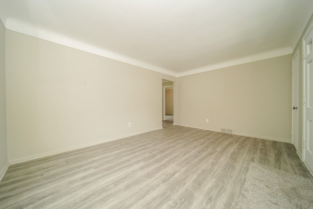 unfurnished room with light wood-style floors, visible vents, and baseboards