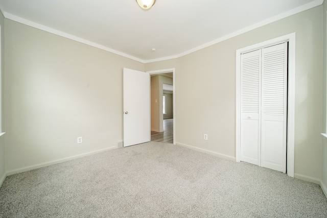 unfurnished bedroom with crown molding, a closet, baseboards, and carpet