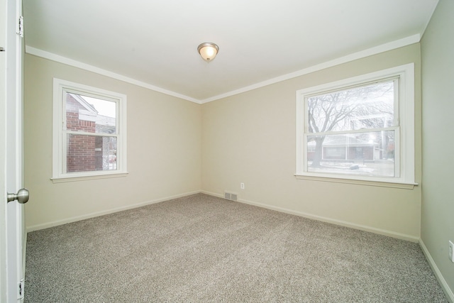 empty room featuring carpet, visible vents, baseboards, and crown molding