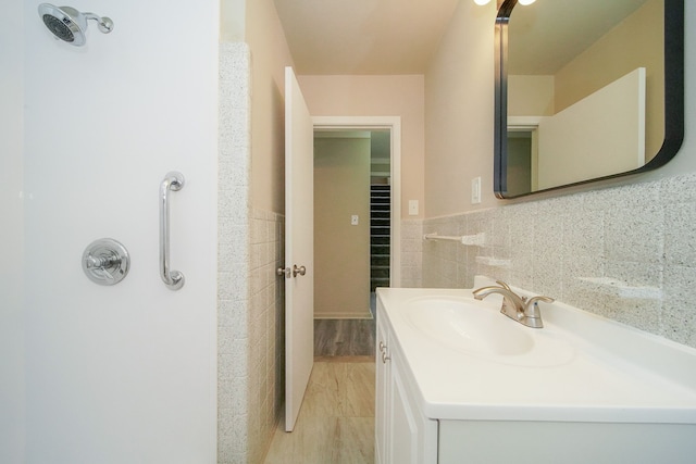 bathroom featuring a wainscoted wall, tile walls, vanity, and wood finished floors