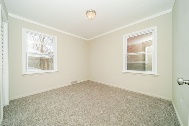 carpeted spare room featuring crown molding, baseboards, and visible vents