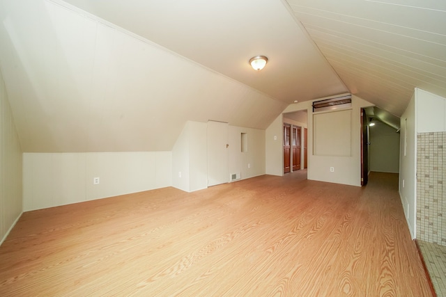 bonus room featuring light wood-style floors, visible vents, and vaulted ceiling