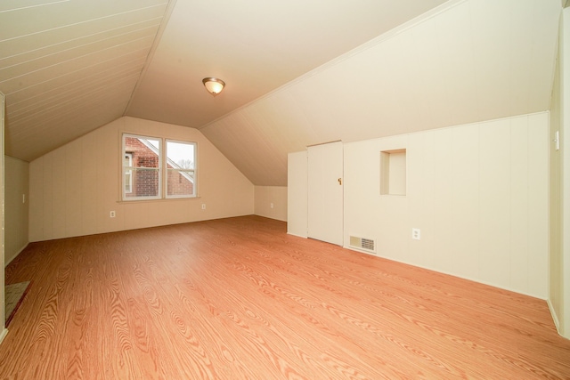 additional living space with visible vents, light wood-type flooring, and vaulted ceiling