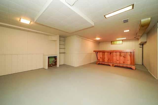 basement featuring a bar, a decorative wall, and visible vents