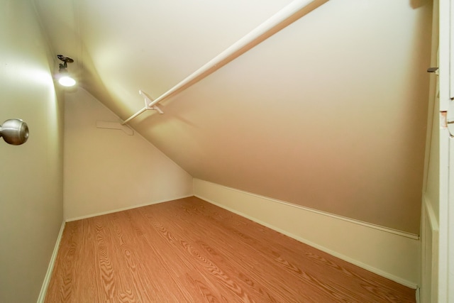 bonus room with light wood-style flooring, baseboards, and vaulted ceiling
