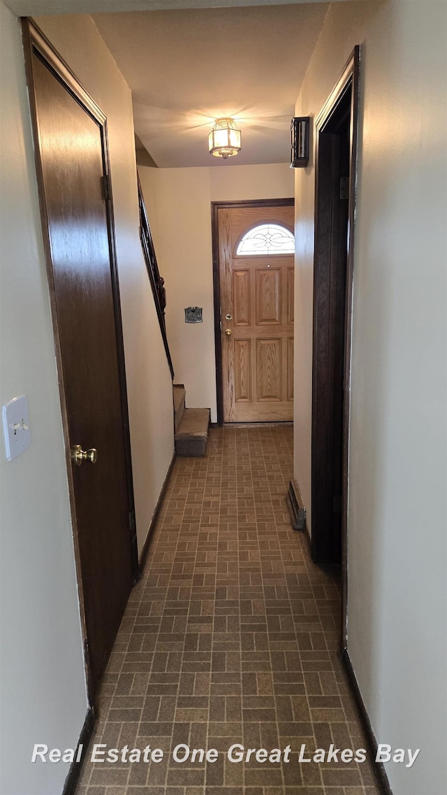 doorway featuring stairs and brick patterned floor