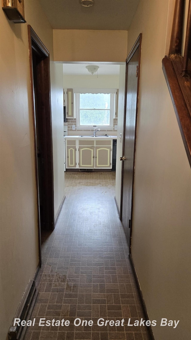 hallway with a sink and brick patterned floor