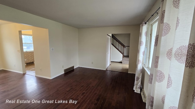 spare room featuring visible vents, baseboards, stairway, and dark wood-style floors