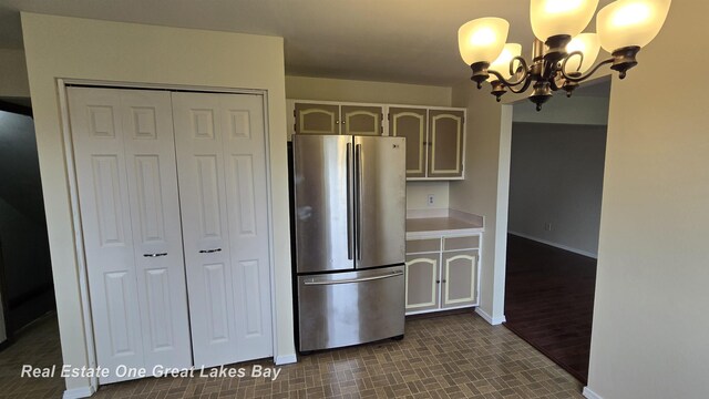 kitchen with light countertops, baseboards, freestanding refrigerator, and a chandelier