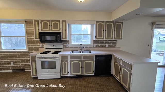 kitchen featuring a peninsula, light countertops, black appliances, decorative backsplash, and a sink
