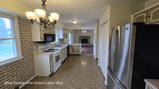 kitchen featuring white range with gas cooktop, black microwave, light countertops, freestanding refrigerator, and a sink