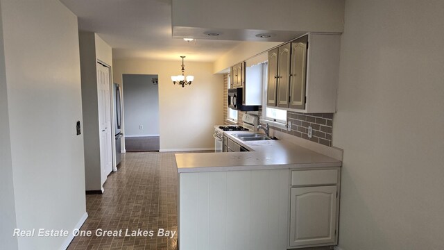 kitchen with baseboards, an inviting chandelier, white gas stove, light countertops, and decorative backsplash
