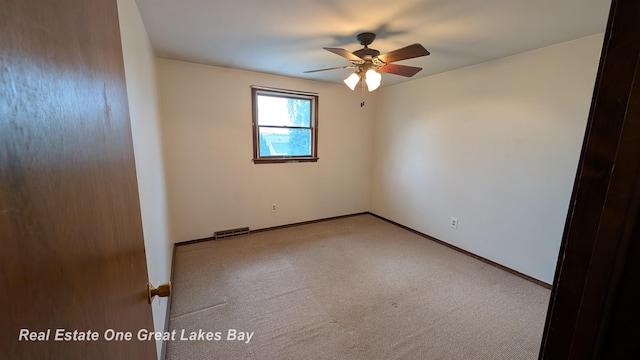 carpeted empty room with visible vents, baseboards, and ceiling fan