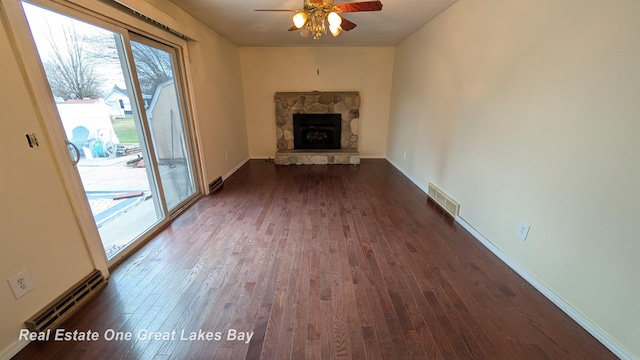 unfurnished living room with a fireplace, visible vents, dark wood-style flooring, and a ceiling fan