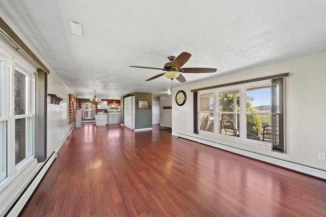 unfurnished living room featuring baseboard heating, ceiling fan with notable chandelier, and wood finished floors