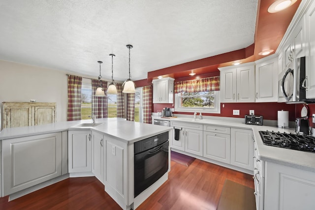 kitchen with light countertops, dark wood-style flooring, a sink, and black appliances