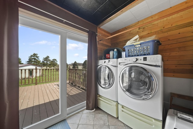 washroom with laundry area, wood walls, washing machine and clothes dryer, and tile patterned flooring