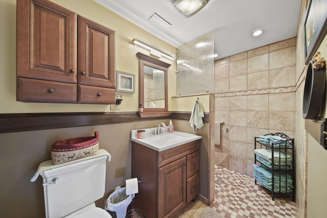 bathroom with toilet, a walk in shower, vanity, and recessed lighting