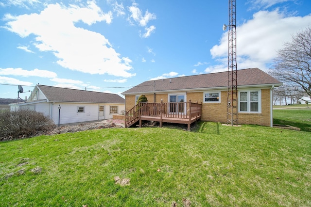 rear view of property featuring a yard, brick siding, and a deck