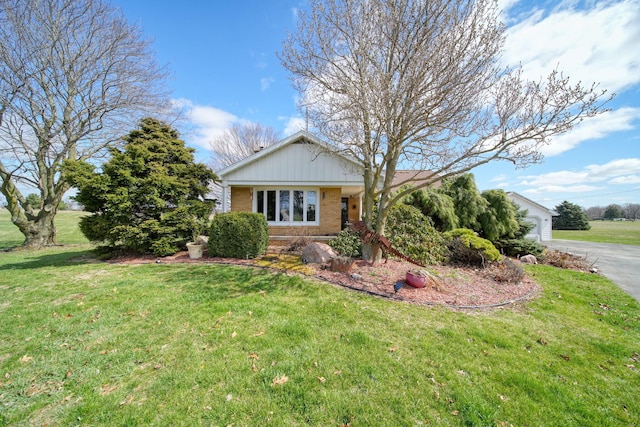 view of front of house with brick siding, a front lawn, an attached garage, and aphalt driveway