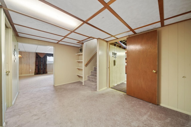 basement featuring carpet flooring, baseboards, and stairs