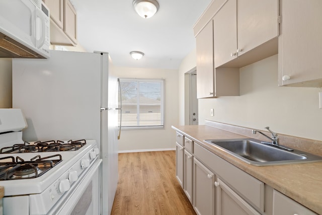 7957 Pine St, Taylor, MI 48180 - kitchen with a sink, light countertops, baseboards, light wood finished floors, and white appliances