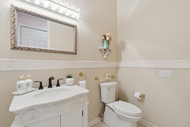 bathroom with toilet, vanity, and baseboards