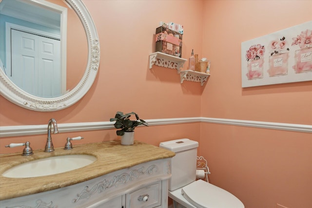 half bathroom featuring vanity and toilet