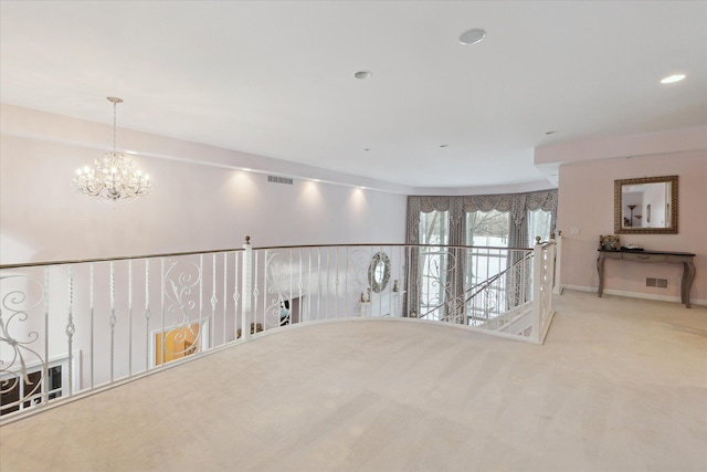 hallway featuring a chandelier, carpet, visible vents, and baseboards