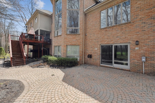 rear view of property featuring a patio area, a wooden deck, stairway, and brick siding