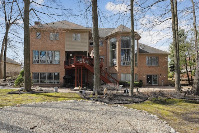 rear view of property with brick siding, a patio area, stairway, and a wooden deck