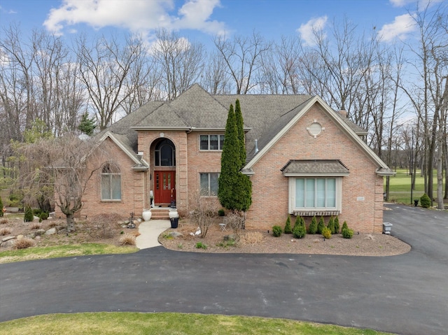 traditional-style home featuring brick siding and roof with shingles