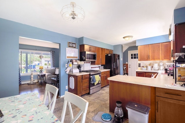 638 Franklin St, Linden, MI 48451 - kitchen featuring stainless steel appliances, light countertops, a peninsula, brown cabinets, and tasteful backsplash