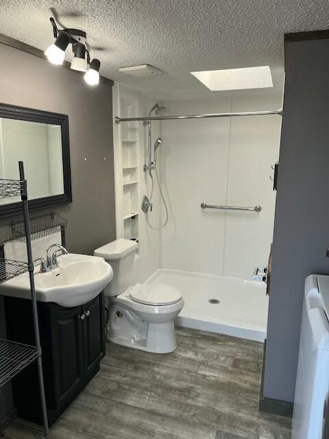 full bathroom with toilet, a shower stall, wood finished floors, and a textured ceiling