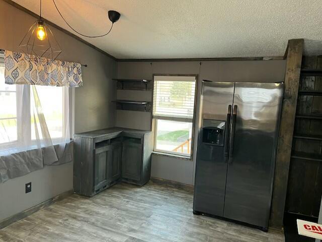 kitchen with a textured ceiling, refrigerator with ice dispenser, lofted ceiling, light wood finished floors, and baseboards