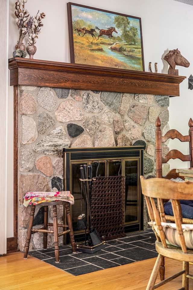 interior details with wood finished floors and a stone fireplace