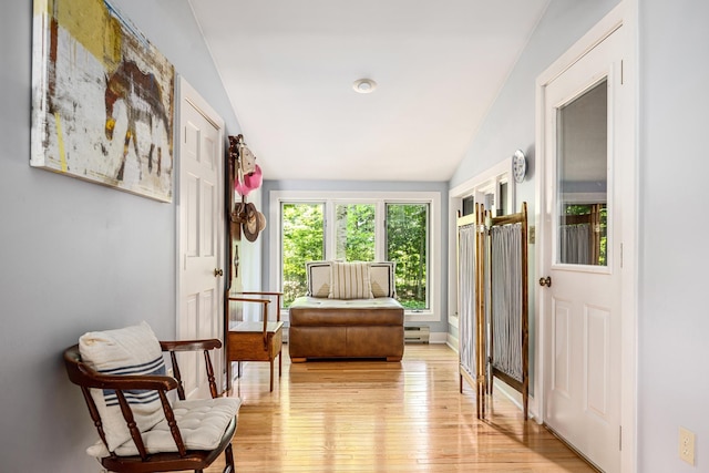 living area with lofted ceiling, light wood finished floors, and baseboards