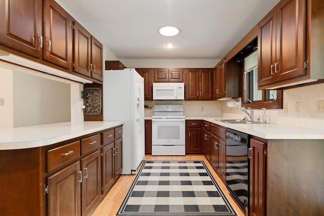 kitchen with light wood finished floors, light countertops, a sink, white appliances, and decorative backsplash