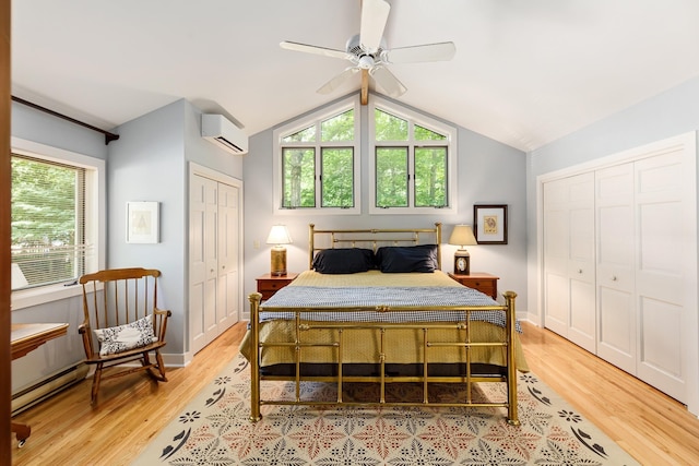 bedroom with a wall mounted AC, lofted ceiling, light wood finished floors, and multiple windows