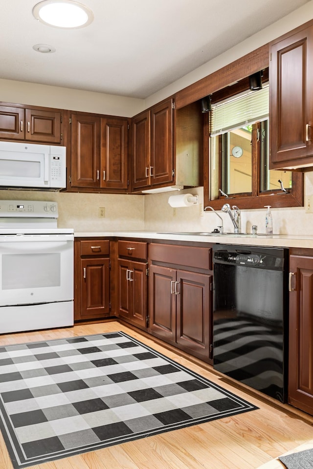 kitchen featuring light countertops, backsplash, a sink, white appliances, and light wood-type flooring