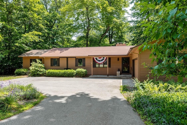 ranch-style house with driveway and a chimney