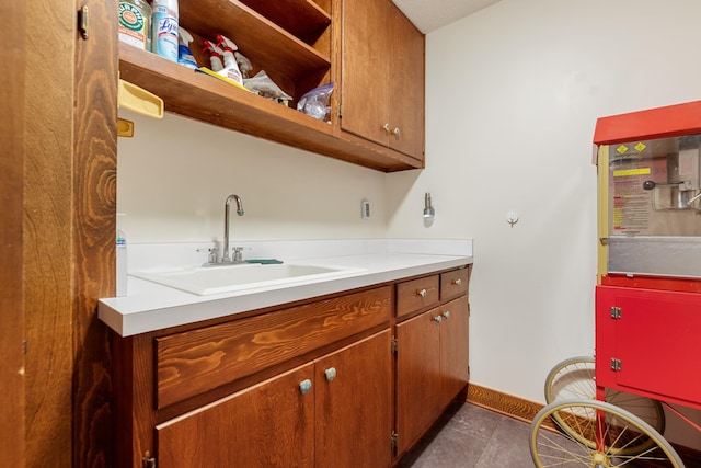 washroom with dark tile patterned floors, baseboards, and a sink