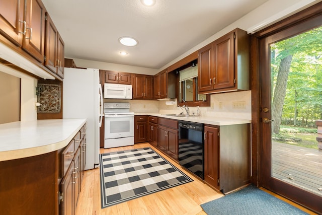 kitchen featuring light wood-style floors, a sink, white appliances, and light countertops
